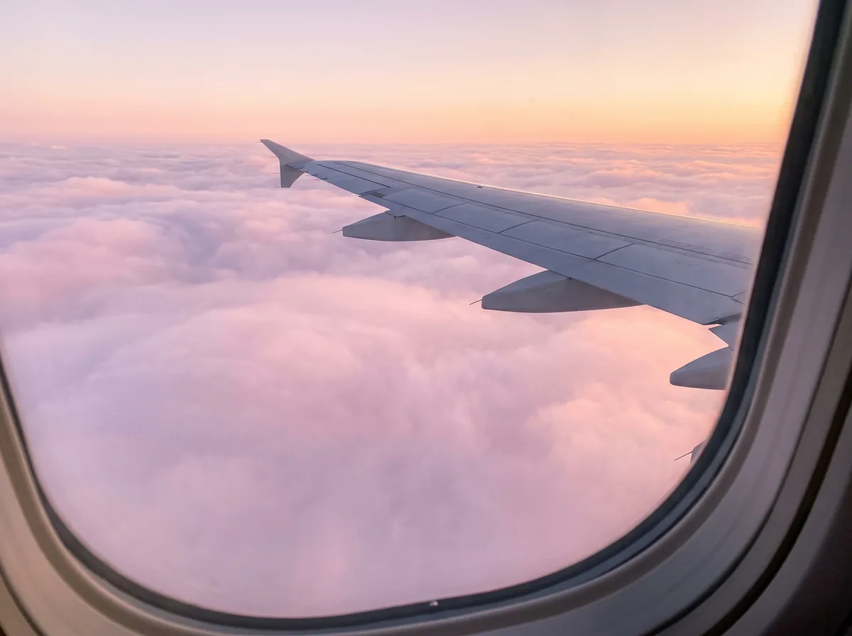 Aripa unui avion deasupra norilor, la răsărit